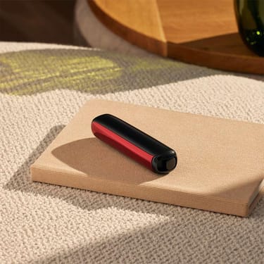 Pannello frontale Ploom AURA Lava Red attaccato al dispositivo su un tavolo.