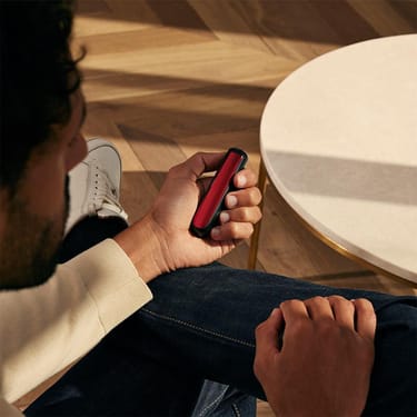 Man holding a Ploom device with Lava Red Front Panel