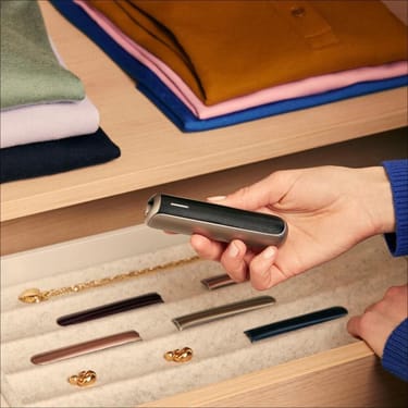 Mano che tiene l'accessorio pannello frontale Ploom AURA Jet Black con motivo Jet Black sul dispositivo.