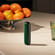Ploom device with Amazon Green Back Cover on a table close to a fruit basket