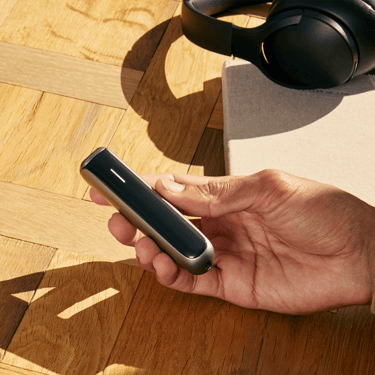 Ploom AURA device with Jet Black front panel held in hand.