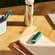 Dispositivo Ploom con Cover Posteriore Teal Electric Pop su un tavolo vicino a un cesto di frutta