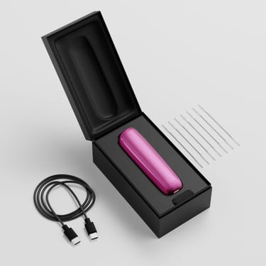 Scatola aperta del Ploom AURA che mostra il dispositivo, il cavo di ricarica e gli stick per la pulizia.