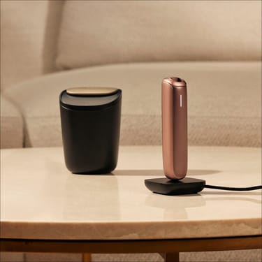 Vassoio grande per stick Ploom accanto a un dispositivo Ploom AURA in carica
