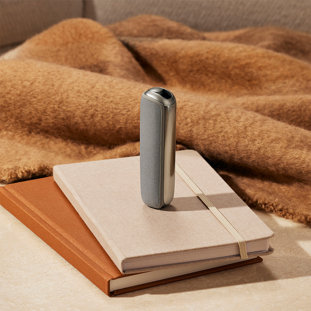 Ploom device with Lunar Silver Back Cover standing top notebooks stack